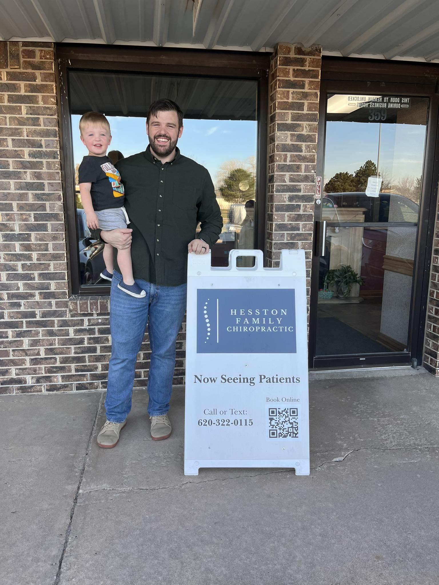 Dr. Zach Beims with son Cyprian outside Hesston Family Chiropractic
